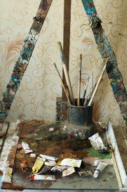 Easel for painting, tubes of oil paint and brushes