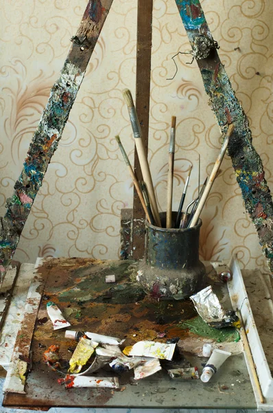 Caballete para pintar, tubos de pintura al óleo y pinceles — Foto de Stock