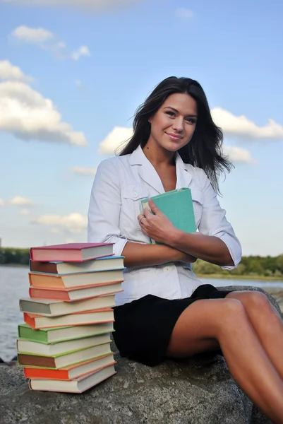 Chica con libros sentados en una roca junto al mar —  Fotos de Stock