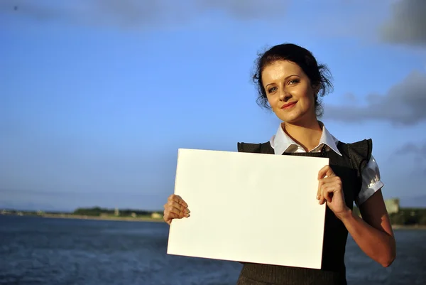 Bella ragazza in possesso di carta bianca. mare sullo sfondo — Foto Stock