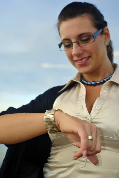 Dívka s brýlemi se dívá na hodinky a s úsměvem — Stock fotografie