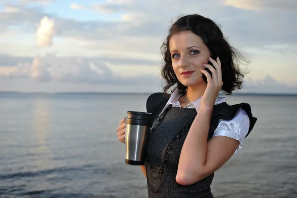 Красива дівчина стоїть на пляжі з чашкою кави — стокове фото