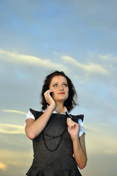 Красивая девушка с мобильным телефоном. небо на заднем плане — стоковое фото
