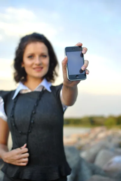 Прекрасна молода жінка, що показує мобільний телефон. зосереджений на телефоні . — стокове фото
