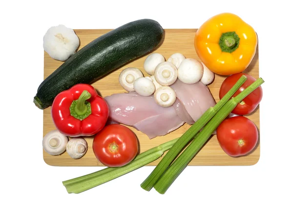 Pollo, cuchillo y verduras en una tabla de cortar, aislados en blanco — Foto de Stock