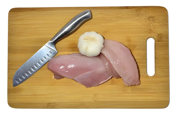 Pollo, cuchillo y ajo en una tabla de cortar, aislado en blanco —  Fotos de Stock
