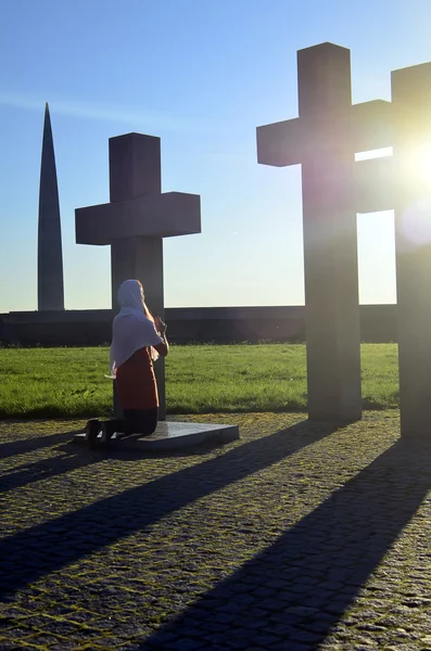 Menina orando na cruz ao pôr do sol — Fotografia de Stock