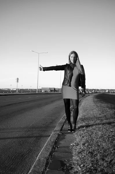 Chica en la carretera esperando un coche, foto en blanco y negro — Foto de Stock