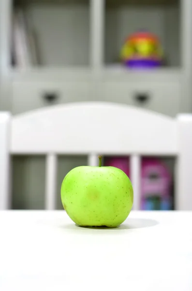 Зеленое яблоко на столе в детской — стоковое фото