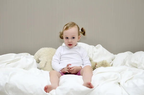 Meisje, zittend op een bed — Stockfoto