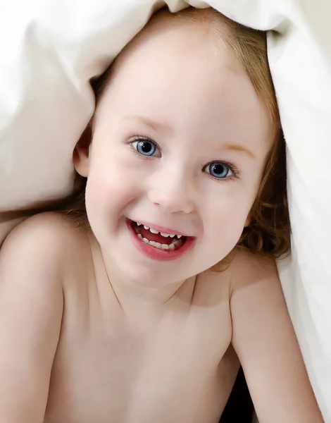 Маленькая девочка смотрит из-под одеяла — стоковое фото