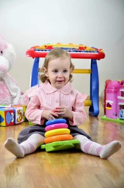 Bambina in una stanza con giocattoli, giocando con la piramide di colore — Foto Stock