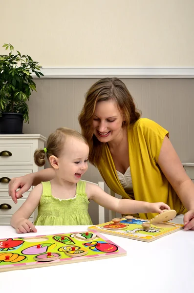 Little girl and mom playing in a children puzzle — Stock Photo, Image