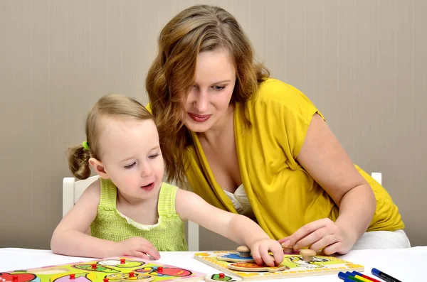 Маленькая девочка и мама играют в детскую головоломку — стоковое фото