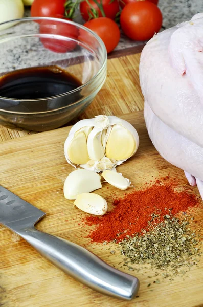 Курица, специи, нож, чеснок и соевый соус на кухонной доске — стоковое фото