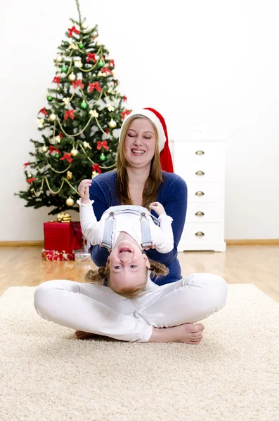 Lille pige og hendes mor har det sjovt til jul - Stock-foto