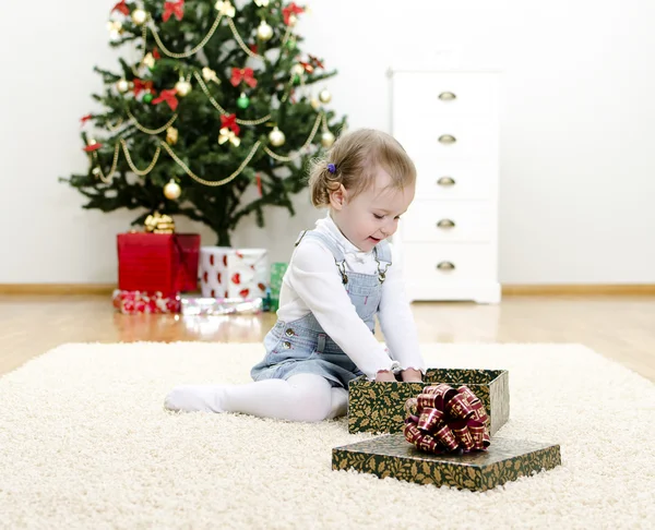 Niña desempaca el regalo en Navidad — Foto de Stock
