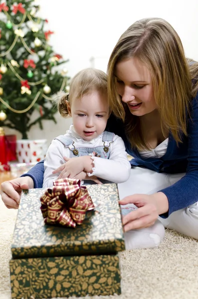 La niña y su madre desempaquetan el regalo en Navidad — Foto de Stock