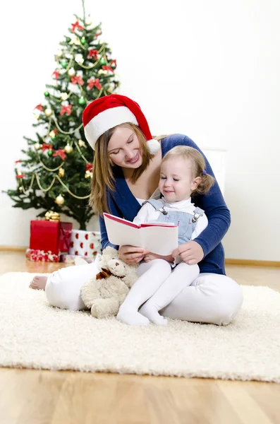 Dziewczynka i jej mama czytanie książki na Boże Narodzenie — Zdjęcie stockowe