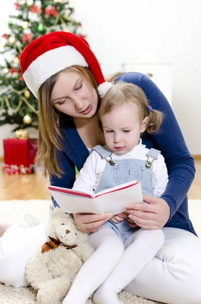 Kız ve onun anne Noel kitap okumak — Stok fotoğraf