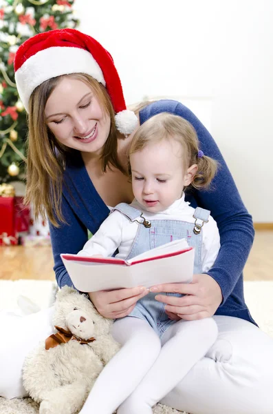 Meisje en haar moeder lezen boek bij Kerstmis — Stockfoto
