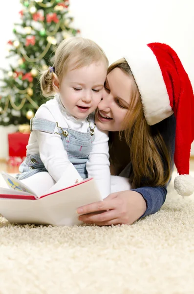 Menina e sua mãe lendo livro no Natal — Fotografia de Stock