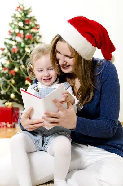 Flickan och hennes mamma läsa bok vid jul — Stockfoto