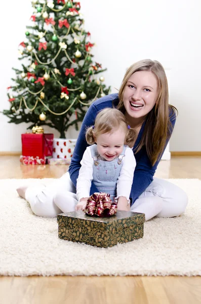 La niña y su madre desempaquetan el regalo en Navidad Fotos De Stock