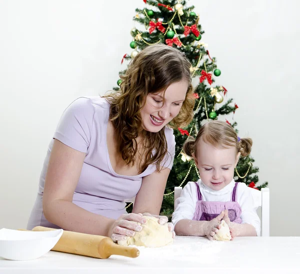 Маленькая девочка и мама готовят рождественское печенье — стоковое фото