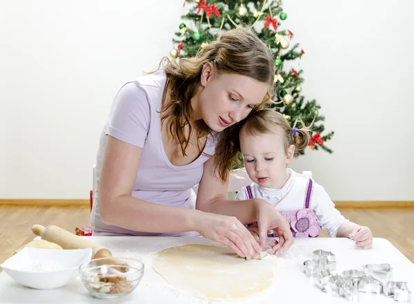 Маленькая девочка и мама готовят рождественское печенье — стоковое фото