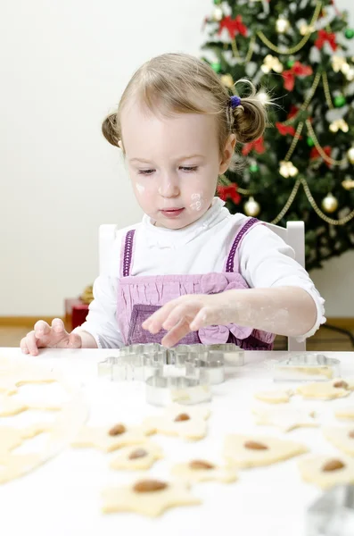Маленькая милая девочка делает рождественское печенье — стоковое фото