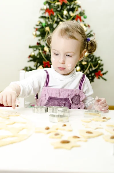 Το μικρό χαριτωμένο κορίτσι κάνει μπισκότα Χριστουγέννων — Φωτογραφία Αρχείου