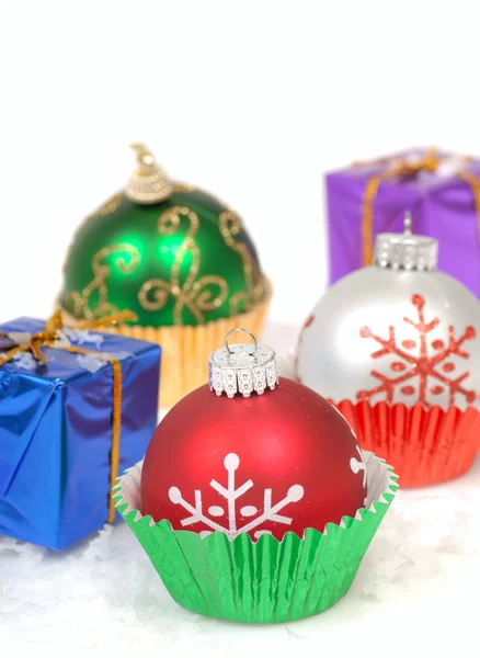 Christmas ornaments in cupcake liners with gifts — Stock Photo, Image