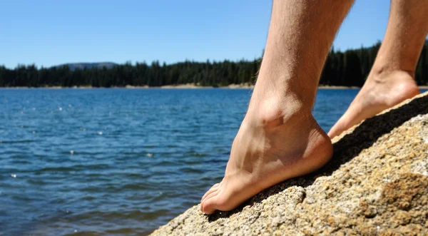 stock image Mans Feet on big rock near lake