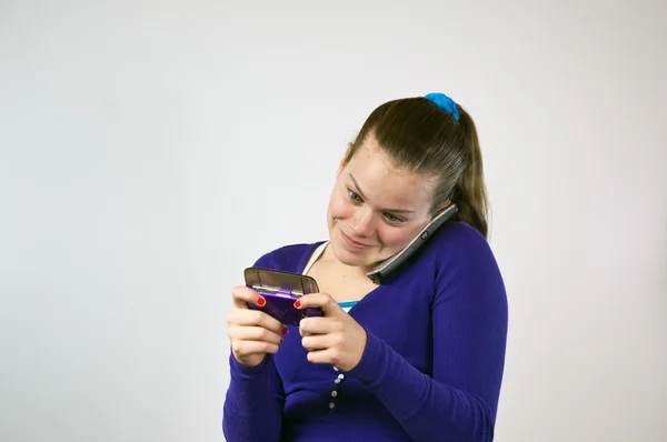 Teen flicka använder två telefoner Royaltyfria Stockfoton