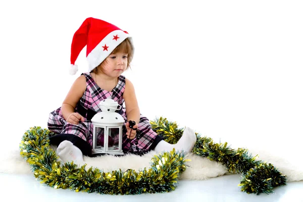 Little girl wearing a Santa hat and playing with baubles — Stockfoto