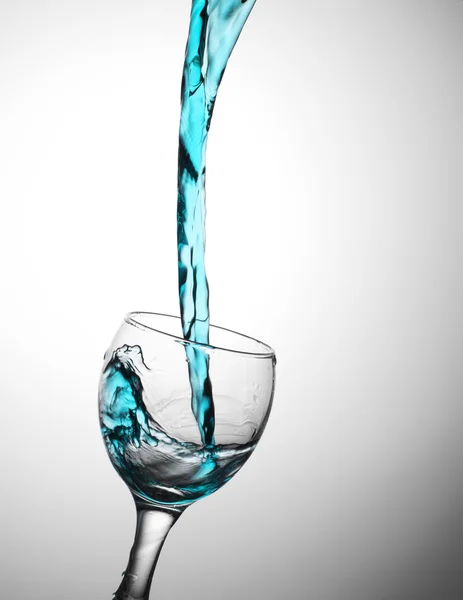 Blue water flows in a glas — Stock Photo, Image