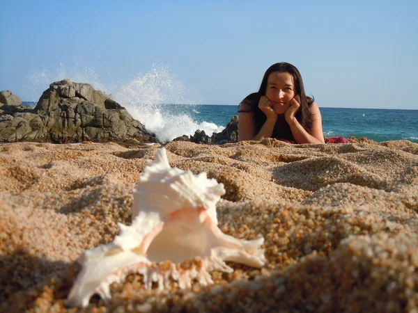 Молодая женщина на пляже и раковина — стоковое фото