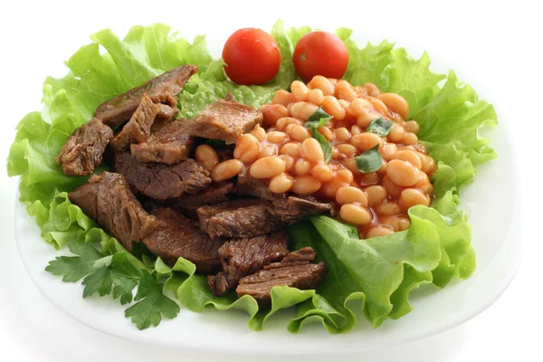 Fried beef with beans on lettuce — Stock Photo, Image