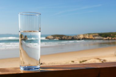 Glass of water with view on beach clipart