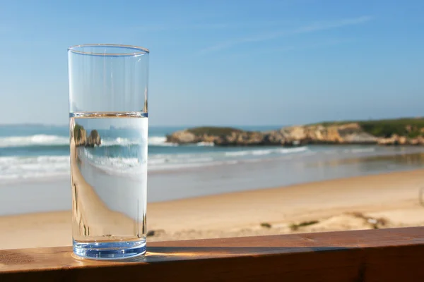 Szklankę wody z widokiem na plażę — Zdjęcie stockowe