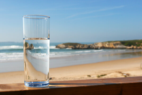 Glass of water with view on beach
