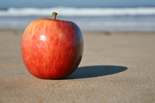 Een apple op zand op strand — Stockfoto