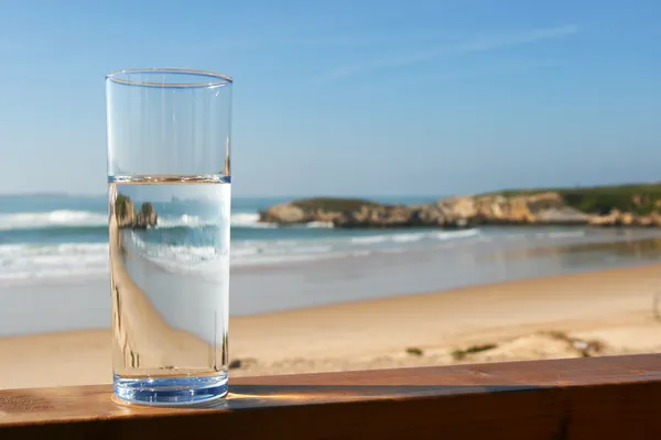 Bicchiere d'acqua con vista sulla spiaggia Foto Stock