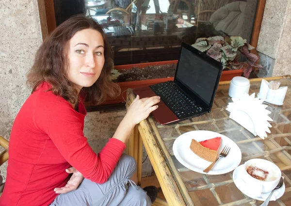 Uma jovem mulher atraente sentada em um café com um laptop — Fotografia de Stock