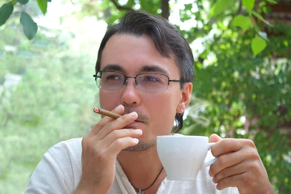 Young man smoking cigar and drinking coffee — Stock Photo, Image