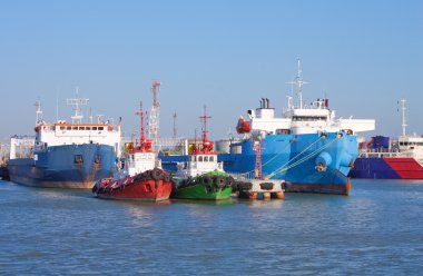 Cargo ships and guard boats docked in port clipart