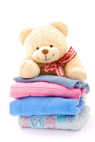 Teddy on stack of kids clothes — Stok fotoğraf