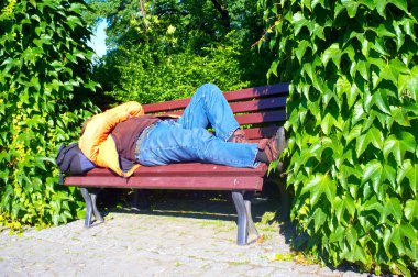 Homless man sleeping on bench clipart