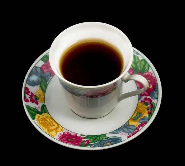 Tasse sehr starken Tee mit Blüten an der Untertasse. — Stockfoto